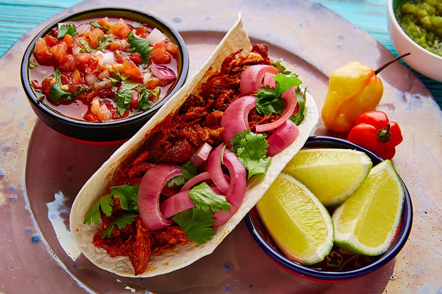 La cochinita pibil se acompaña de cebolla roja y limón. Foto cortesía.