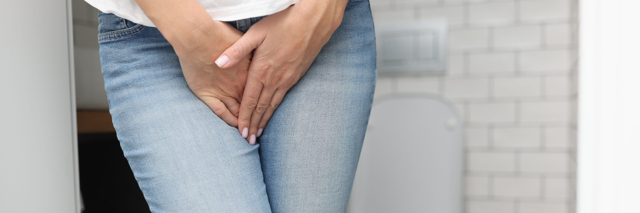 Female hands between legs in jeans close-up